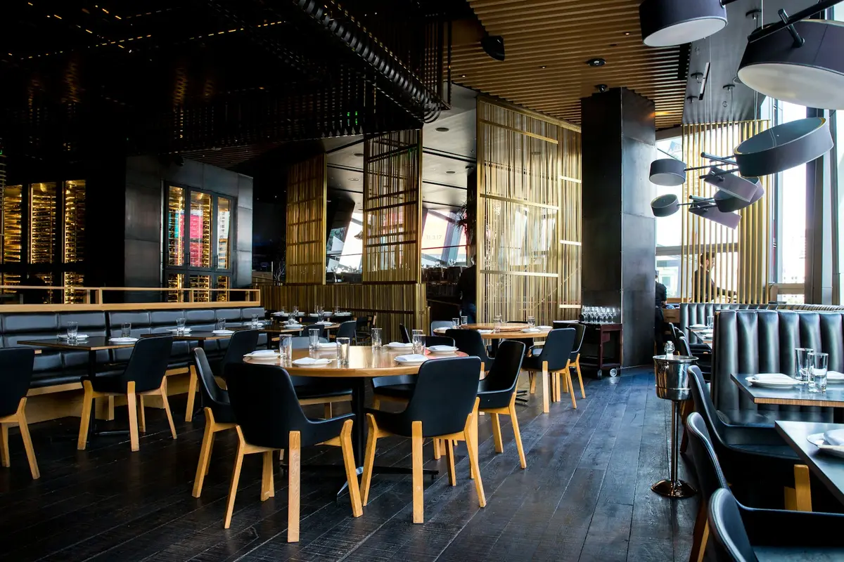 Empty pub interior with wooden bar counter, stools and pendant lights during daytime
