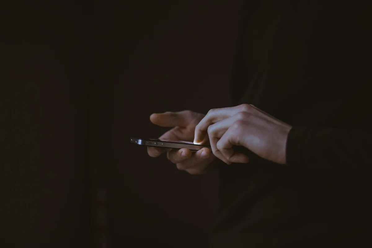 Silhouette of a person holding up a smartphone against a bright colourful backdrop